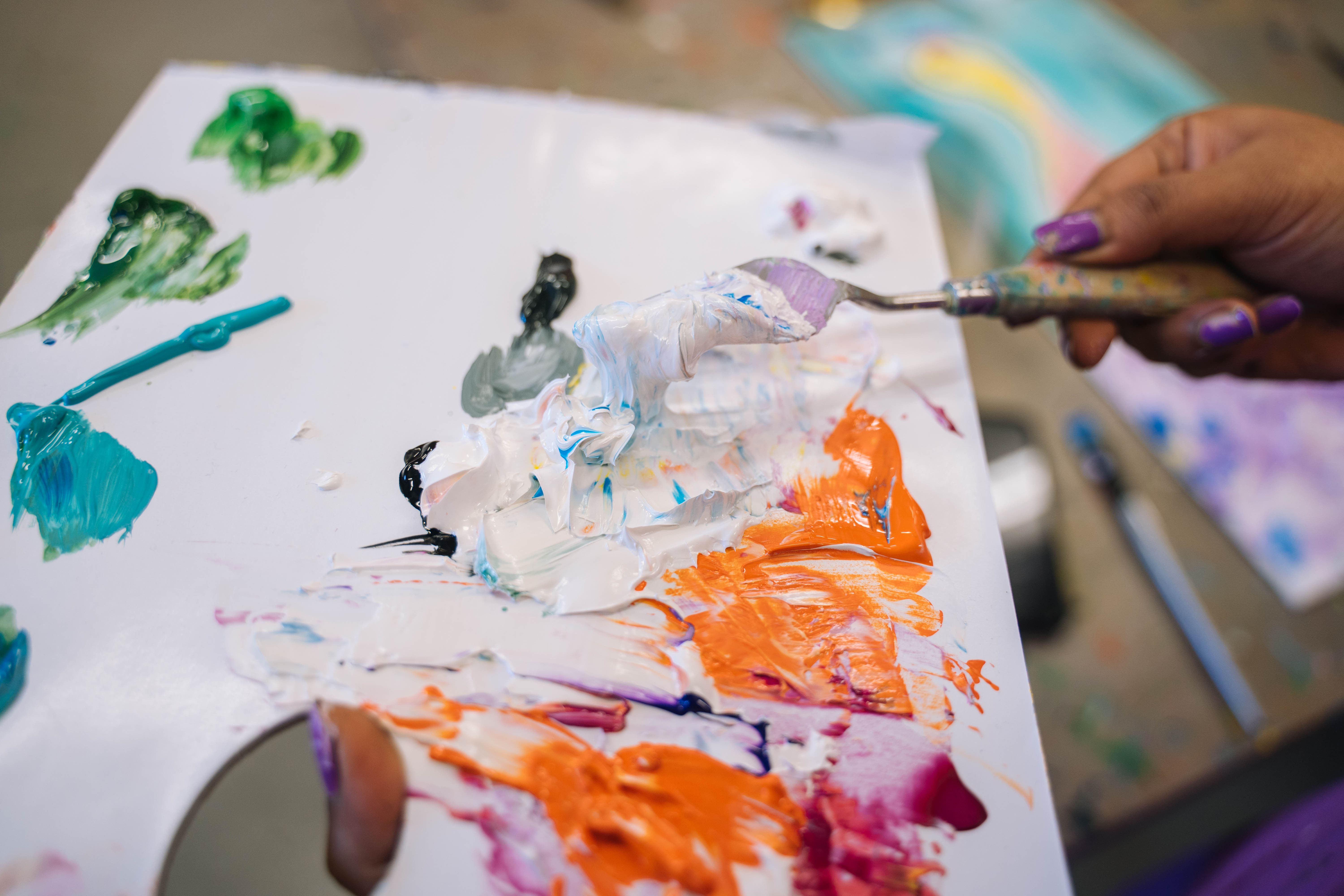 A variety of different oil paints being mixed on a palette